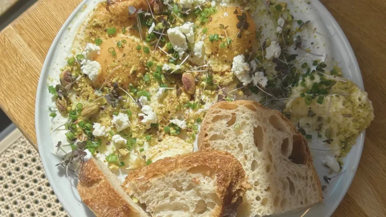 Pyszne śniadanie w restauracji Przesada w Krakowie – kremowe jajka z masłem chili i pistacjami oraz chrupiące pieczywo.